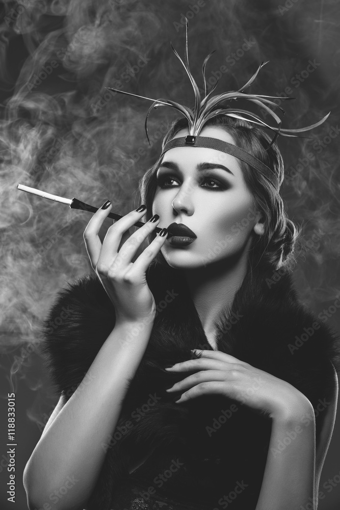 Fototapeta premium Beautiful girl with smoky eyes and red lips holding cigarette