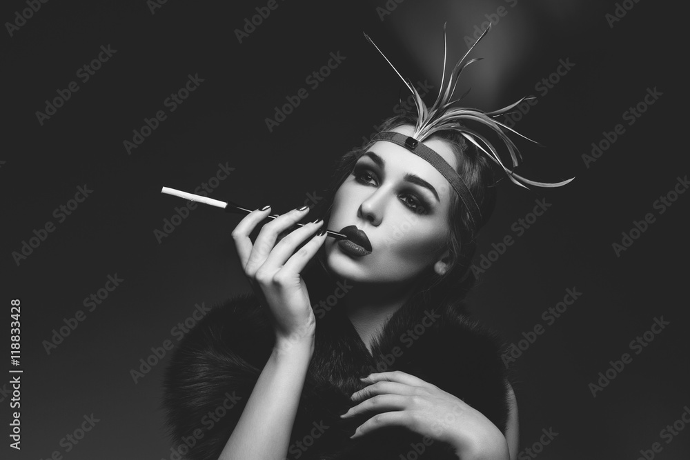 Fototapeta premium Beautiful girl with smoky eyes and red lips holding cigarette