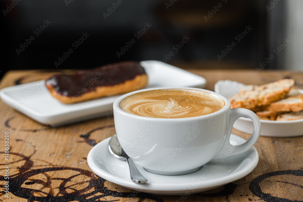 Fototapeta premium cappuccino flatwhite coffee with eclair on table