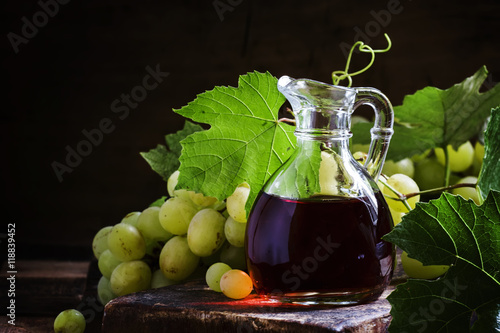 Wine vinegar in a glass jug, dark vintage wooden background, sel