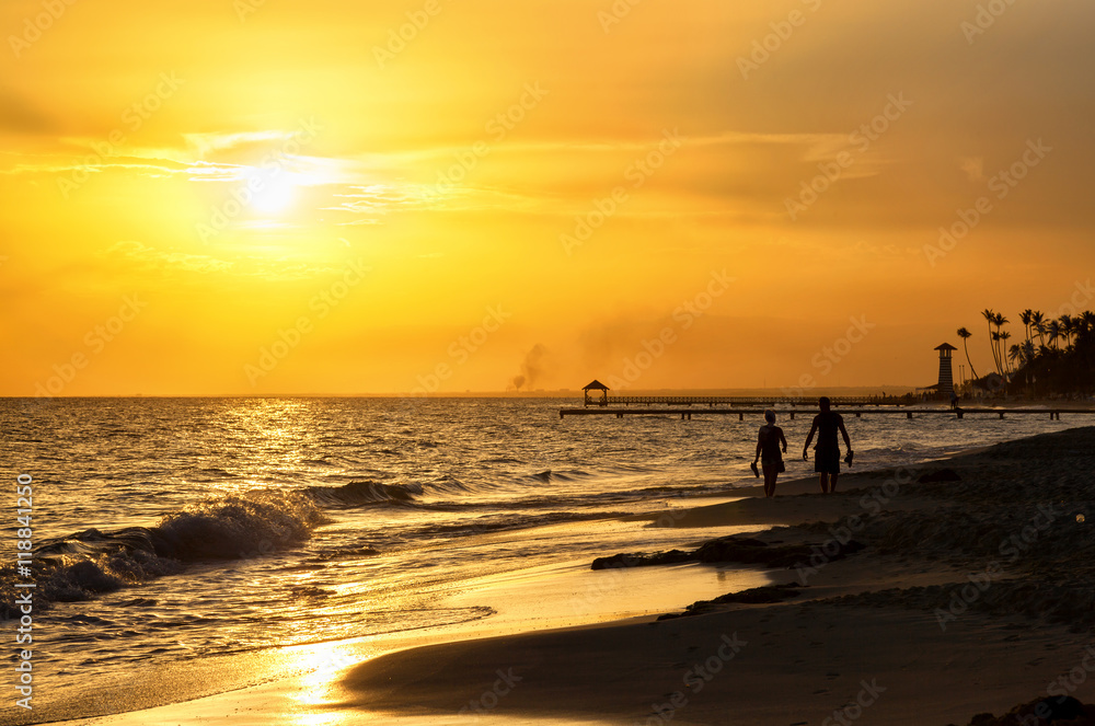 Silhouette of children running along the coastline. Caribbean sea beach sunset. Tropical beach in Caribbean sea, Dominican Republic. Couple are waiting sunset in Caribbean beach. .