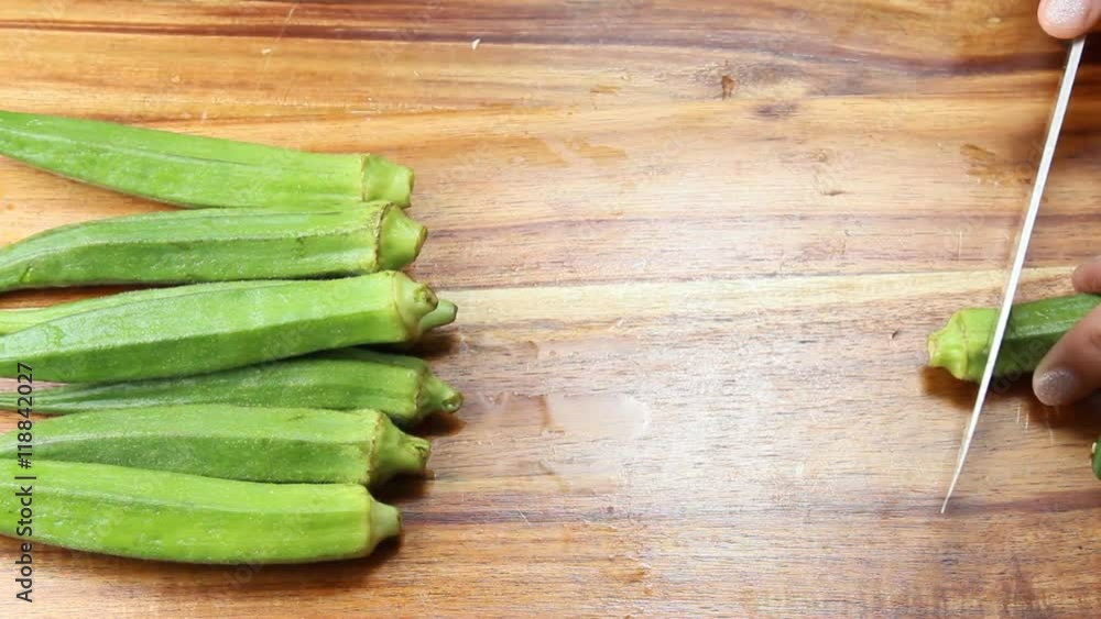 Chopping fresh Okra on a wooden cutting board Chopping fresh Okra on a wooden cutting board