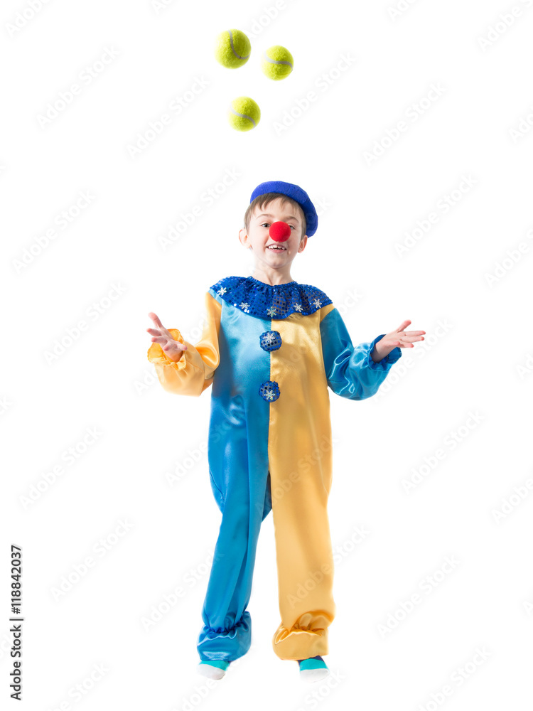 Little boy in clown suit juggling three balls and smiling on a white background