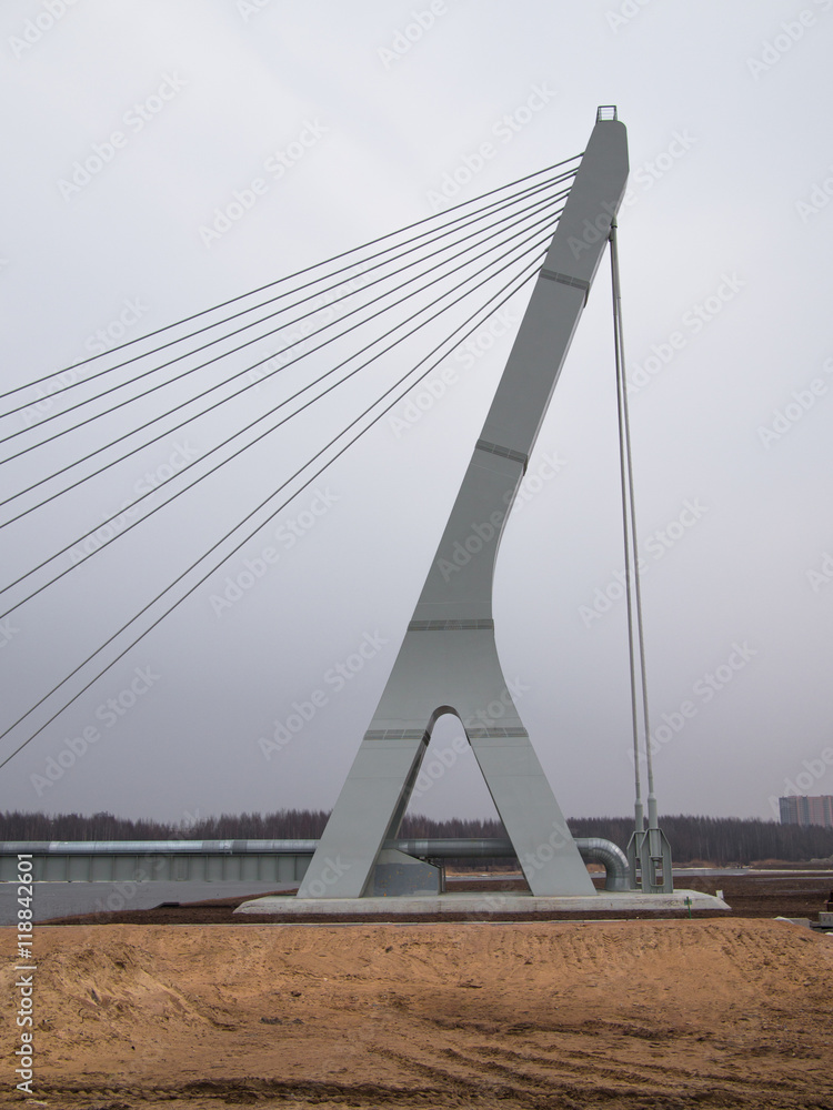 Obraz premium Big and new cable-stayed bridge hanging over the river on the background of buildings under construction and tower cranes