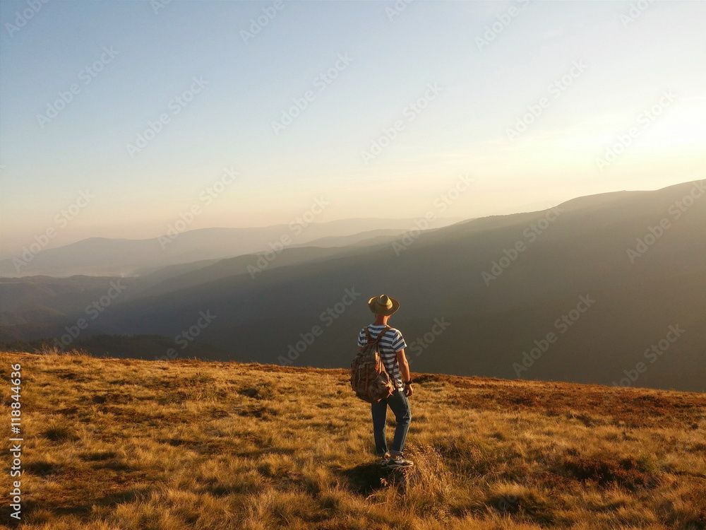 Man, travallerwith a backpack & hat in the mountains Man, travallerwith a backpack & hat in the mountains