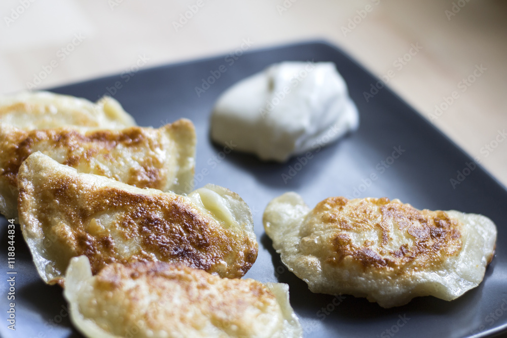 Fried dumplings (called pierogi) with sour cream. Traditional polish food. Fried dumplings (called pierogi) with sour cream. Traditional polish food.