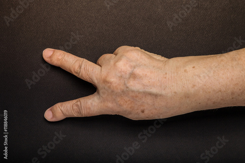 Hands of elderly woman on black background. Toned