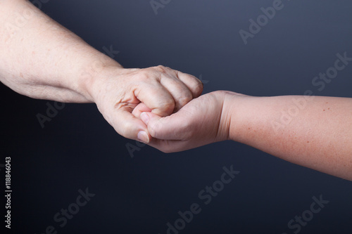Hands of elderly and young women on black background