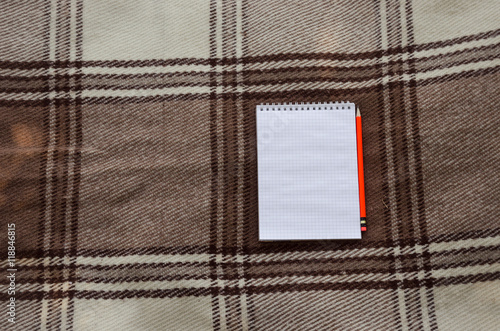 notebook with pencil and notes on coverlet in flat lay.