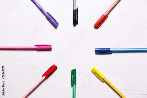 Colorful pens on natural white wooden background.