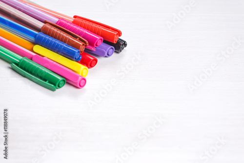 Colorful pens on natural white wooden background.