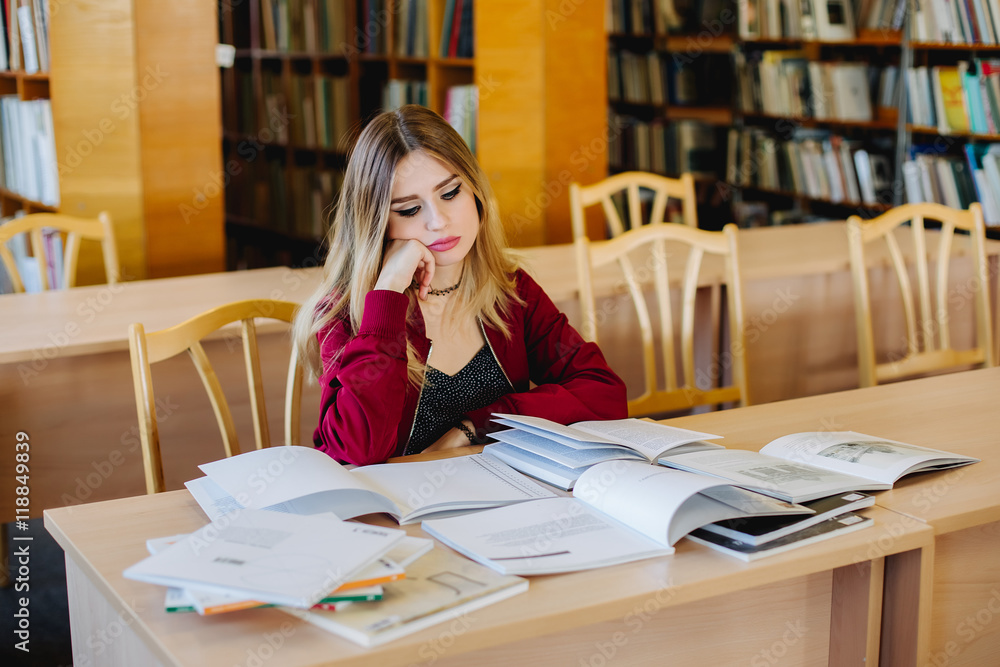 Bored and tired attractive female student sitting at desk in old university library preparing for exam and reading books. Education process. Fatigue concept. Bored and tired attractive female student sitting at desk in old university library preparing for exam and reading books. Education process. Fatigue concept.