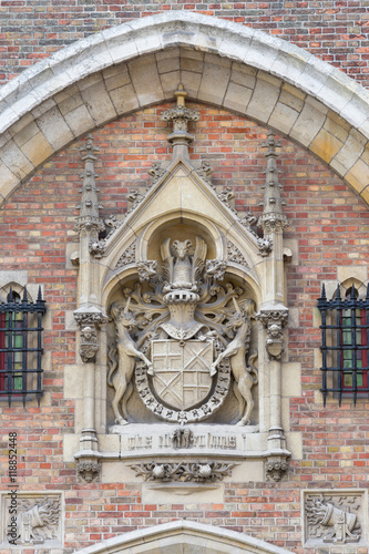 Brugge, Belgium - August 10, 2016: Elaborate mural of Coat of Arms at the gate to Gruuthuse Mansion, now museum. Beige stone against bricks. photo