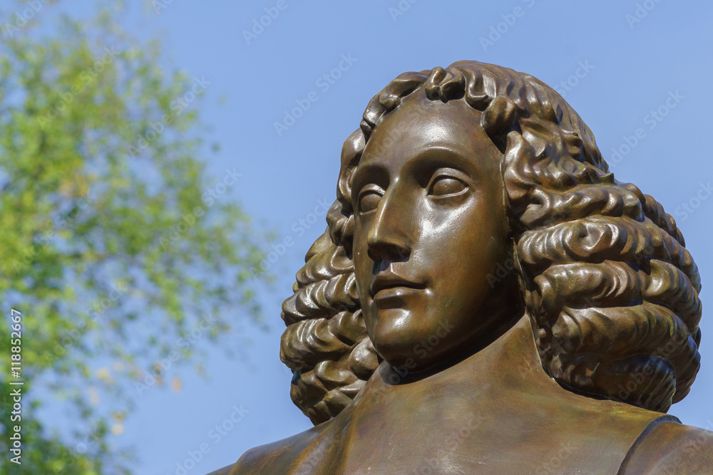 Amsterdam, the Netherlands - August 16, 2016: The famous philosopher Baruch Spinoza has his statue near the Bijvoetbrug. Detail of bronze shows serious looking man with long curly hair.