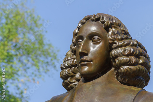 Amsterdam, the Netherlands - August 16, 2016: The famous philosopher Baruch Spinoza has his statue near the Bijvoetbrug. Detail of bronze shows serious looking man with long curly hair. photo