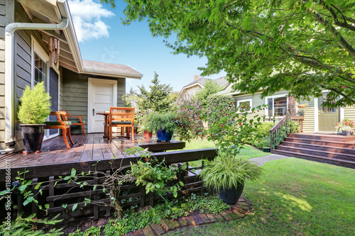 View of guest house with wooden deck and nicely trimmed garden