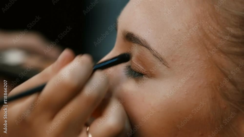 Eye makeup woman applying eyeshadow powder.Eyes Makeup.Make-up.Eyes shadows. Eye shadow brush.Make-up artist makes make-up of eyes of a young woman.Make-up artist with a brush for the face makes the