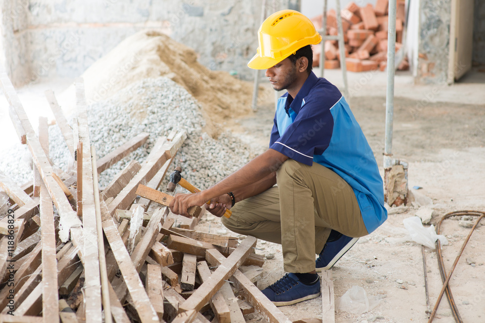 indian male contractor on site using hammer indian male contractor on site using hammer