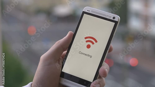 man holding a smart phone that connects to wifi. With traffic lights in the background