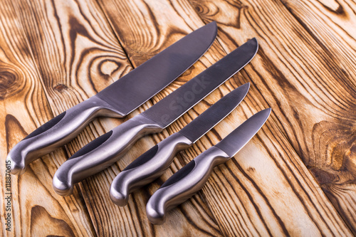 set of shiny metal kitchen knives on a wooden table