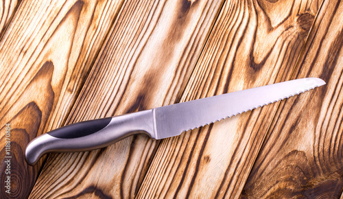 Canvas Print shiny metal kitchen knife for cutting bread on wooden table