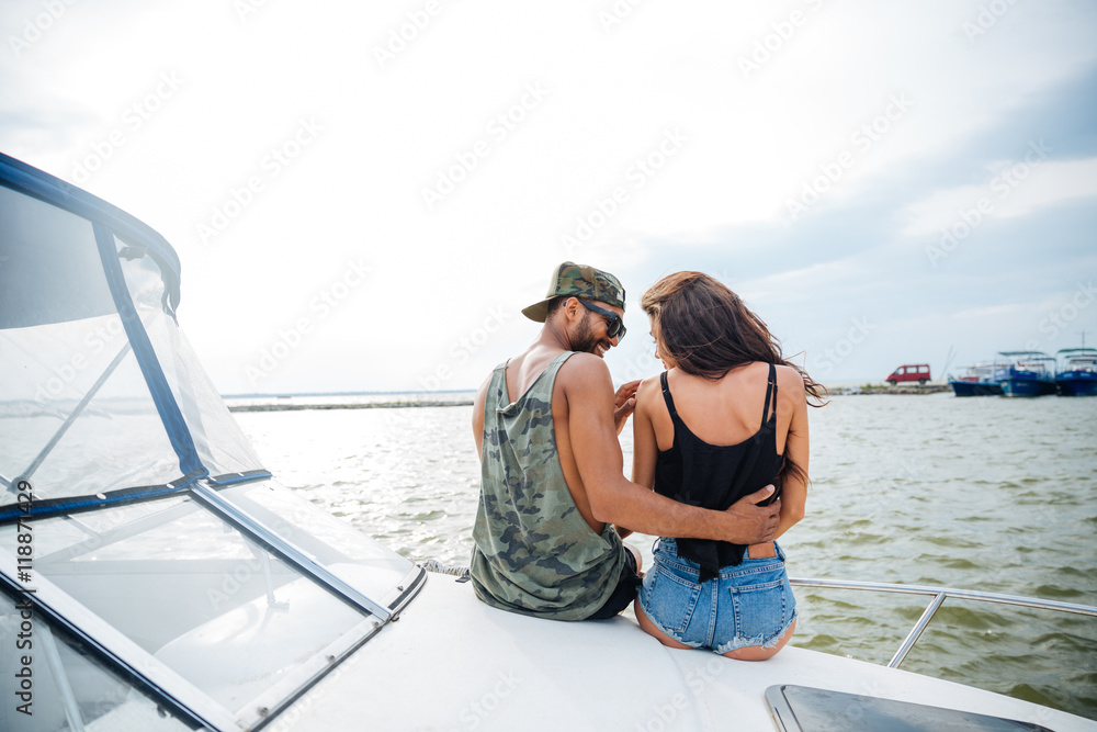 Beautiful loving young couple sitting and hugging on yacht