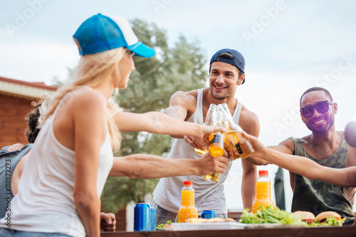 Cheerful young friends drinking beer and celebrating outdoors