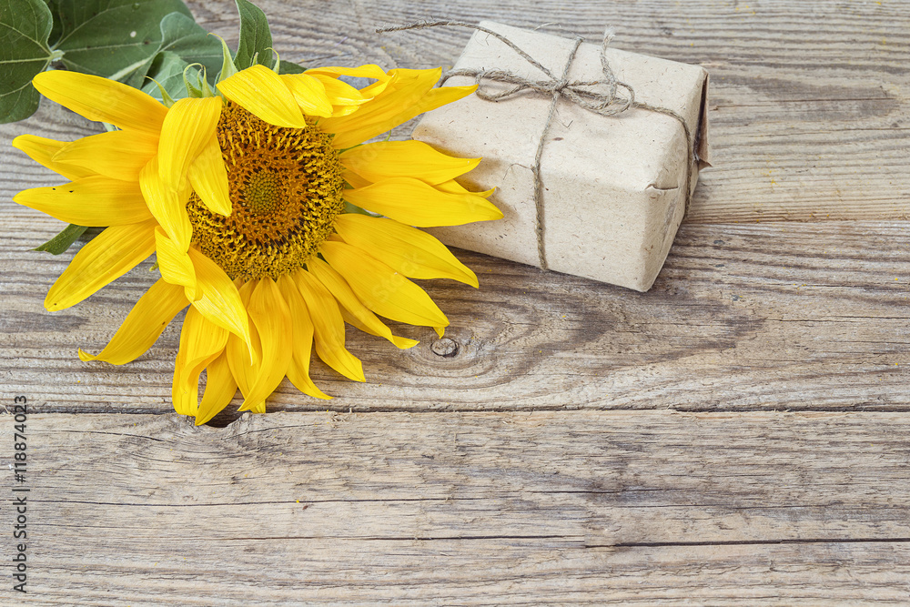 Fototapeta premium Background with yellow sunflowers and gift box on old wooden boa