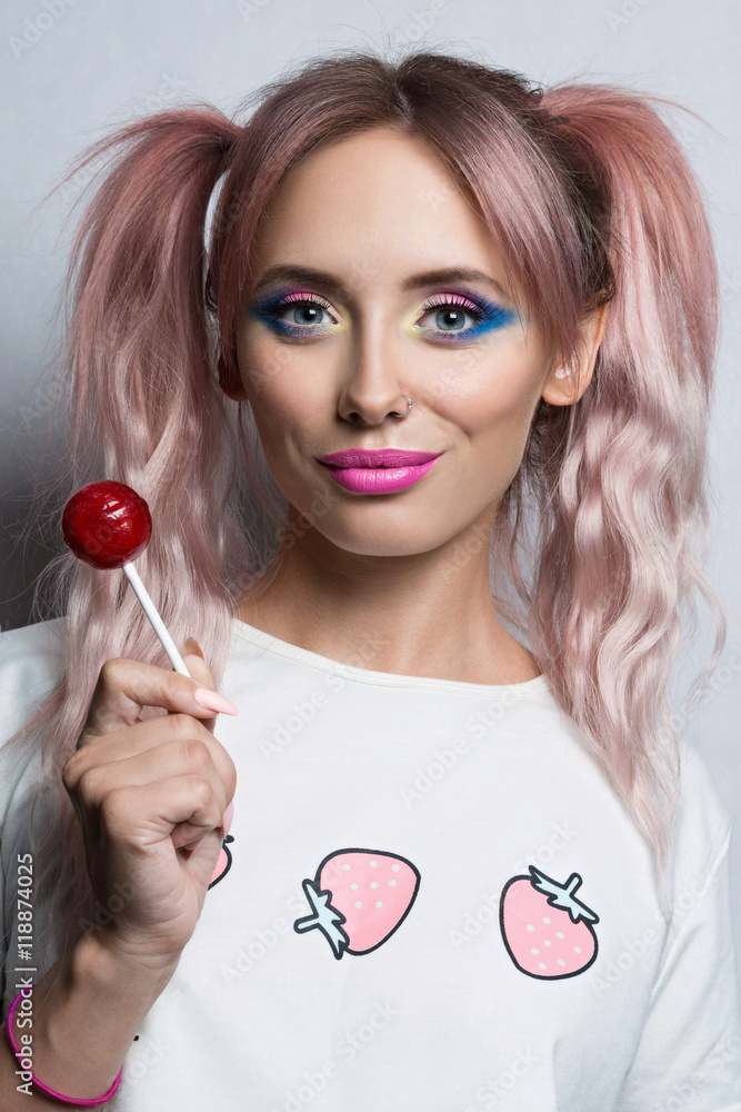 Beauty fashion model girl with two pink ponytail hairstyle Eating colourful  lollipop. Young funny woman with pink nail and colourful make-up isolated  on white background Stock Photo | Adobe Stock