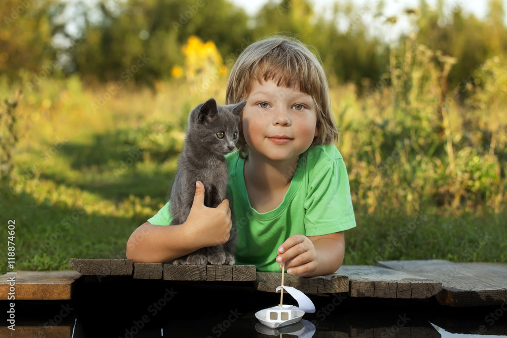 boy and his beloved kitten playing with a boat from pier in pond boy and his beloved kitten playing with a boat from pier in pond