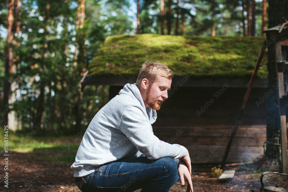 Obraz premium a man sitting in the woods next to the hut