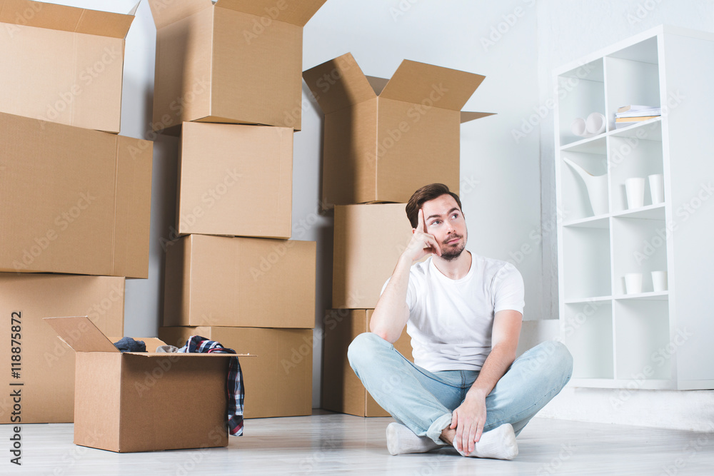Moving in house. Man dreams sitting on the floor in the background box.