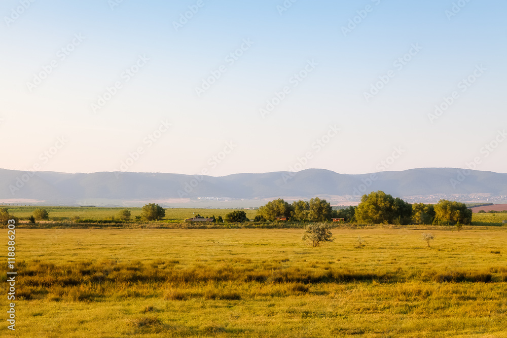 Landscape - field with houses close to hills on a Sunny day in s