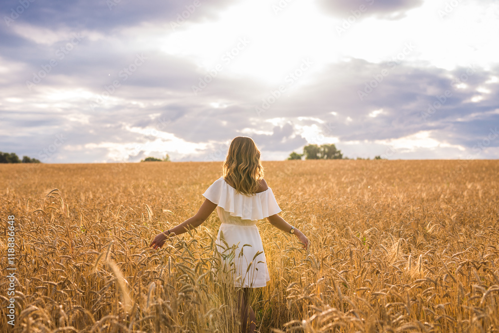 Fototapeta premium Woman with arms outstretched in a wheat field