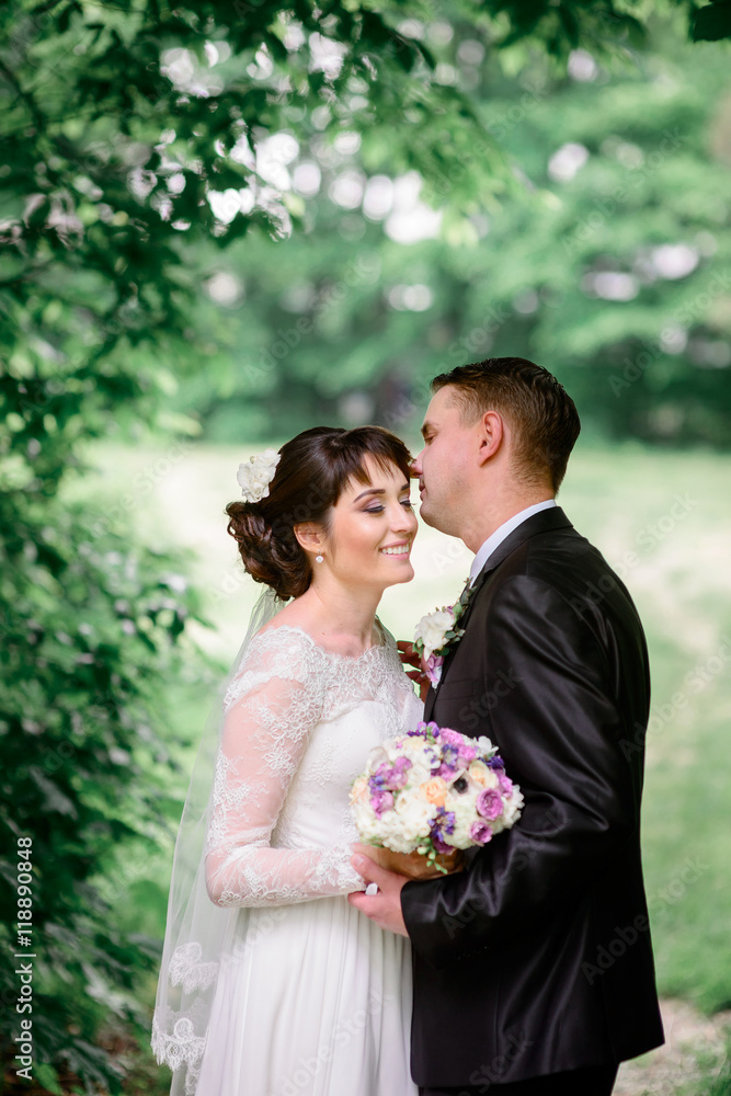 Bride smiles sincerely while groom tries to kiss her forhead sta