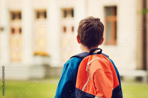 Boy with rucksack infront of a school building. Child with a backpack