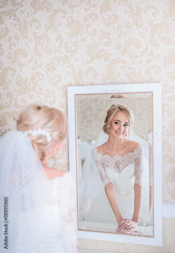 Stunning blonde bride looks in white mirror