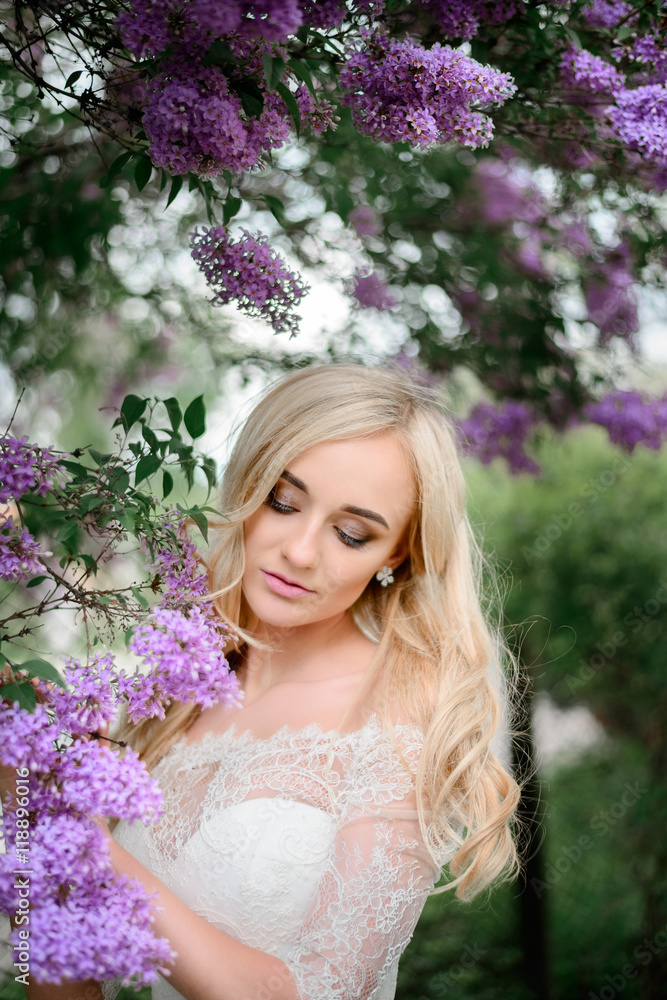 Fototapeta premium Stunning blonde bride stands with closed eyes before the branche
