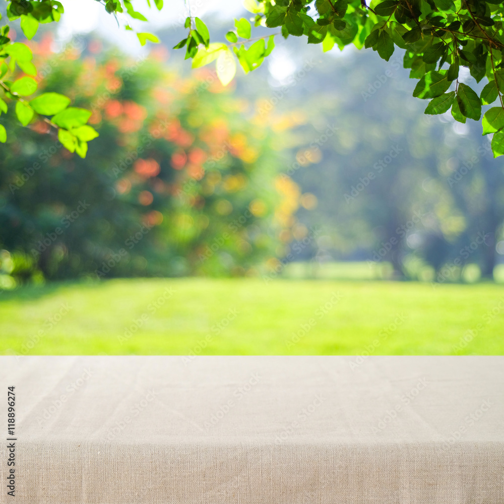 Empty table with linen tablecloth over blur park  background