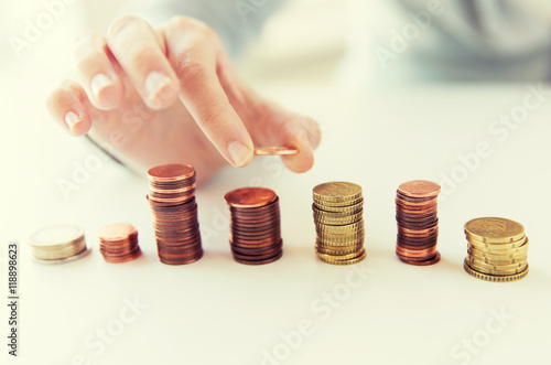 close up of female hand putting coins into columns photo