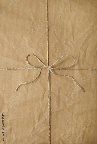 A full page of creased brown parcel paper texture with string bow