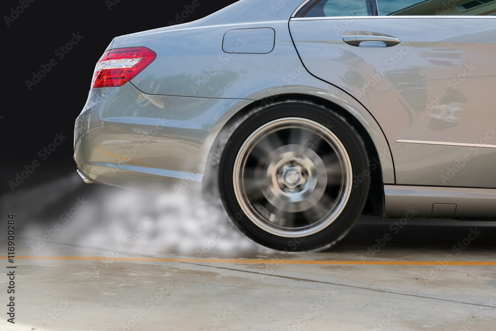 Closeup of the rear wheel of a car that spin and cause smoke.