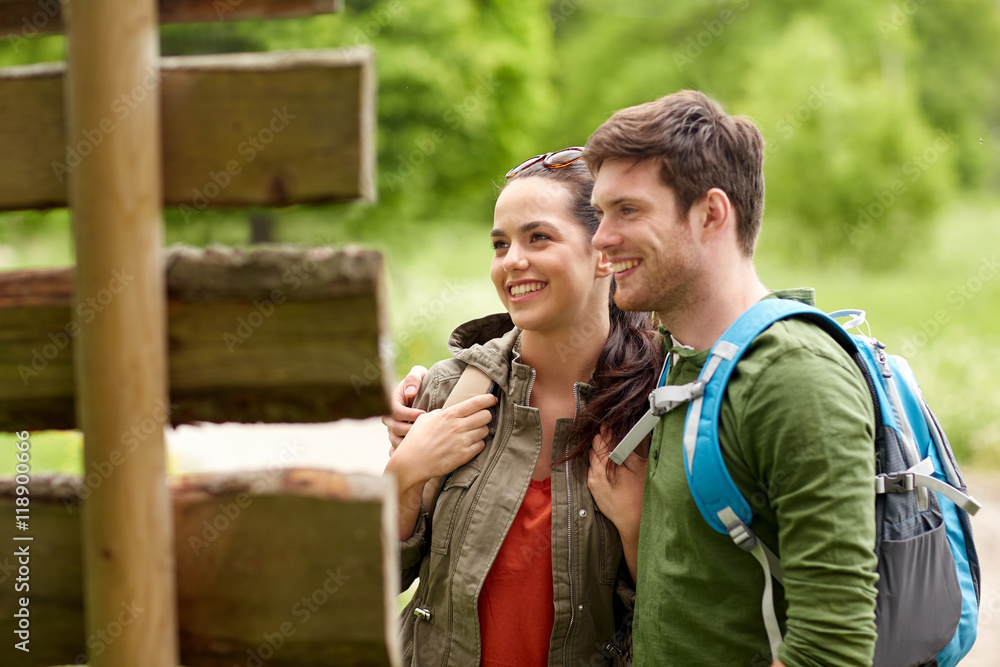 smiling couple at signpost with backpacks hiking smiling couple at signpost with backpacks hiking