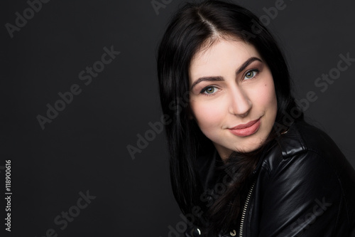 Closeup portrait of beautiful brunnette model woman smiling for camera while posing isolated on black background in studio.