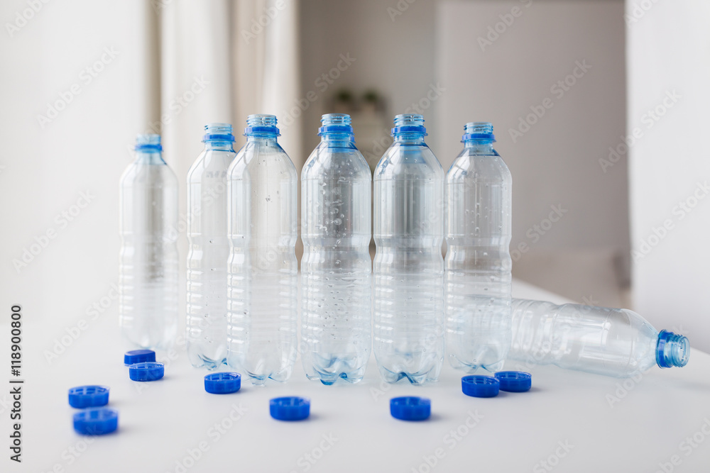 close up of empty water bottles and caps on table close up of empty water bottles and caps on table
