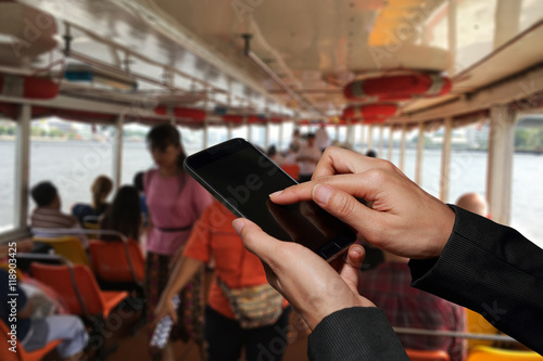 Woman hand hold and touch screen smart phone, cellphone on blurred abstract passenger ships background as communication and transportation concept.