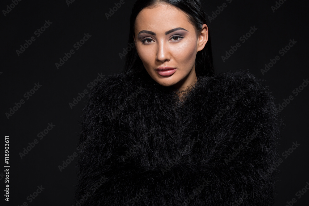 Portrait of gorgeous brunette model woman looking at camera in studio. Beautiful lady in black fur posing isolated on black background. Portrait of gorgeous brunette model woman looking at camera in studio. Beautiful lady in black fur posing isolated on black background.