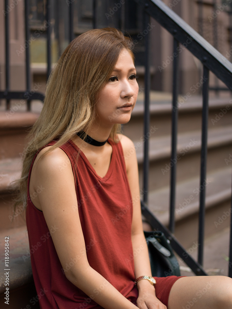 Young Asian woman in city sitting