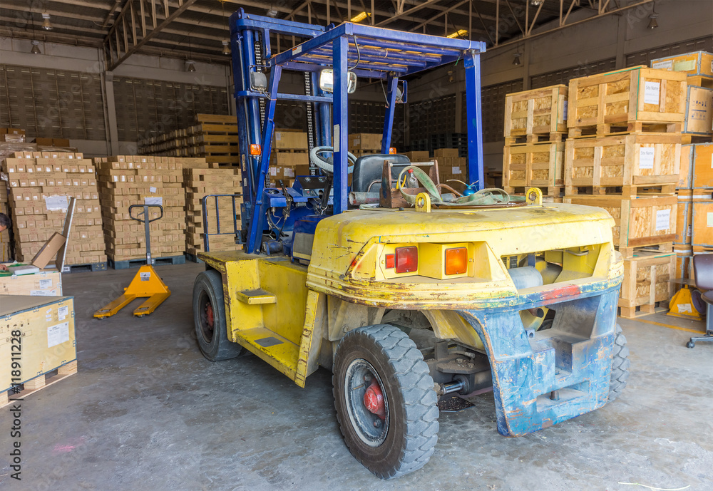Old forklift vehicle used in industrial warehouse for lifting and moving heavy materials. It is also called lift or fork truck.