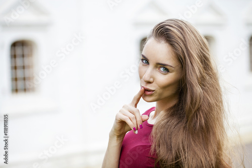 Young beautiful brunette woman has put forefinger to lips as sig